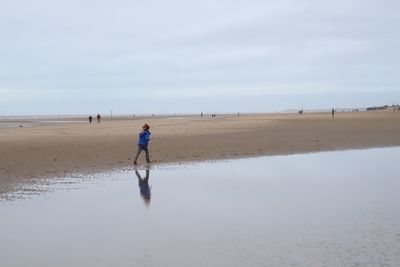 Rear view of man on beach against sky
