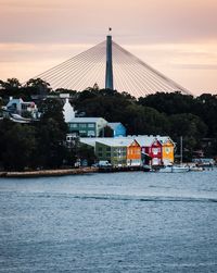 View of buildings by river against cloudy sky