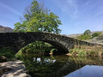 Arch bridge over river against sky