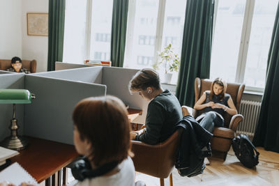 Teenage boy sitting near female students in library