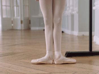 Low section of woman standing on hardwood floor