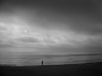 Mid distance view of man walking at beach against sky
