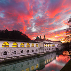 Arch bridge over river against buildings during sunset