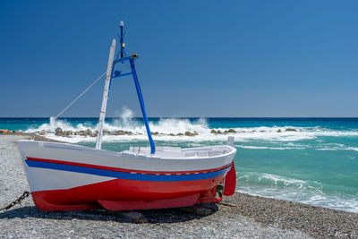 Boat moored on beach against sky