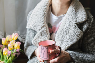 Midsection of woman holding coffee at home