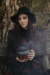 Young woman wearing hat while standing against plants