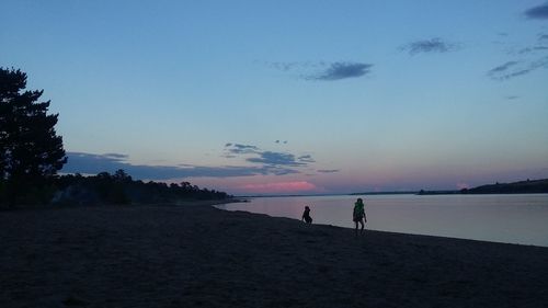 Silhouette people standing on beach against clear sky