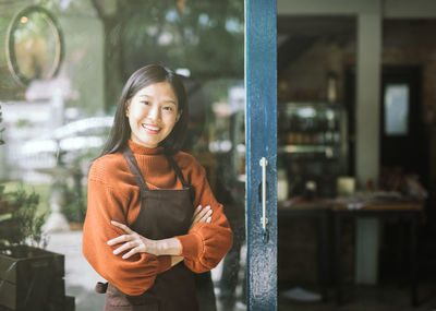 Portrait of beautiful woman smiling while standing outside cafe