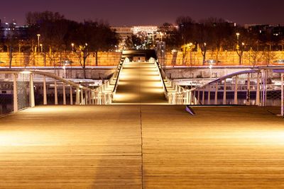 Illuminated bridge over river in city at night