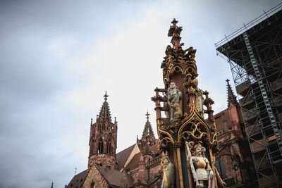 Low angle view of statue amidst buildings against sky