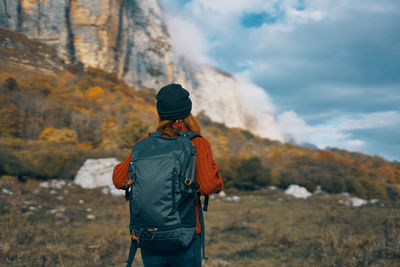 Rear view of man standing on mountain against sky