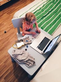 High angle view of girl playing with clay by laptop on table at home