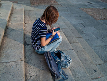 Side view of teenage girl using mobile phone while sitting on steps