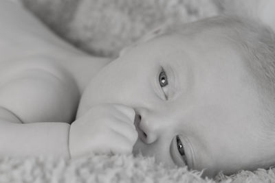 Close-up portrait of cute baby girl lying on bed