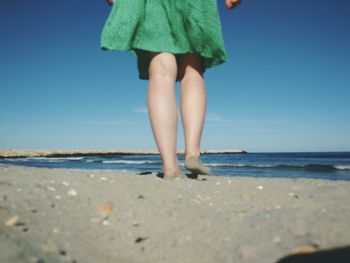 Low section of woman on beach against clear sky