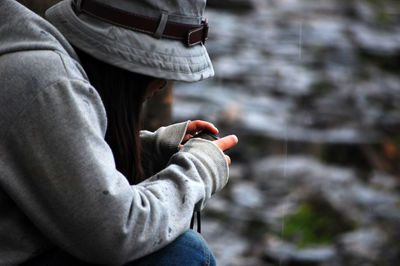 Side view of woman using mobile phone while sitting outdoors