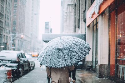 Rear view of man walking on city street in snow