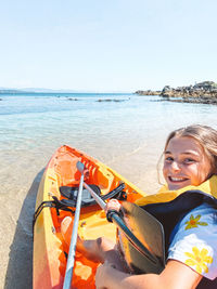 Portrait of smiling young woman on beach against sky