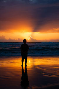 Silhouette man standing on beach during sunset