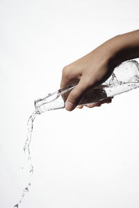 Close-up of hand holding glass over white background