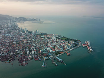 High angle view of illuminated cityscape by sea against sky