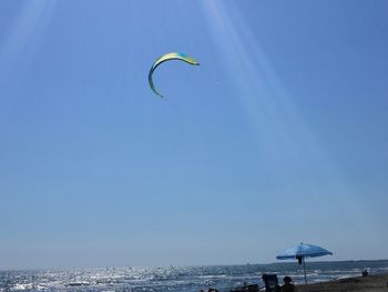 Man paragliding over sea against clear blue sky