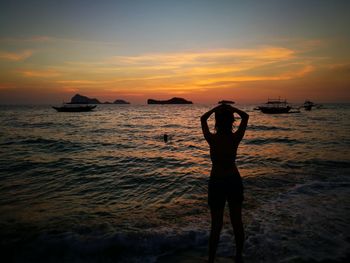 Silhouette woman standing on beach against sky during sunset