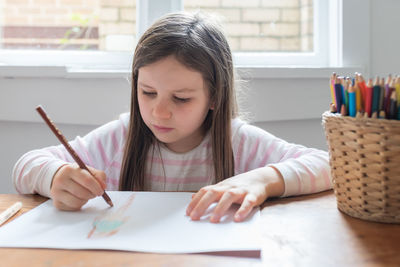 Girl looking away while sitting on table