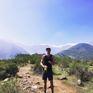 Young man eating banana while standing against landscape