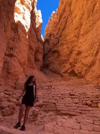 Full length of teenage girl standing amidst rock