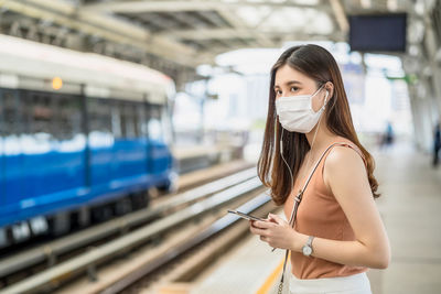 Woman using phone while standing on train