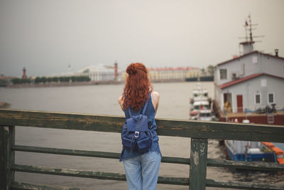 Rear view of woman standing by railing against sky