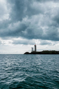 Lighthouse by sea against sky