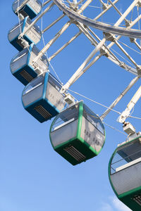 Closeup of colorful cabins of giant ferris wheel in amusement park against blue sky