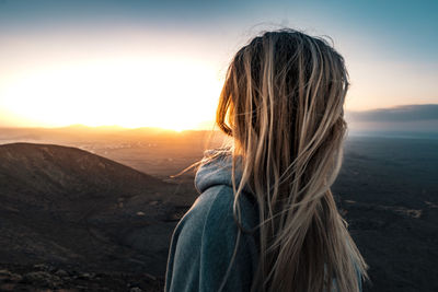 Side view of woman looking at landscape during sunset