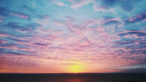 Scenic view of sea against cloudy sky at sunset