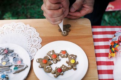 Cropped hands icing gingerbread cookie at table