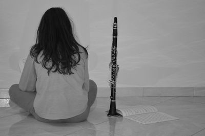 Rear view of woman with clarinet sitting on floor