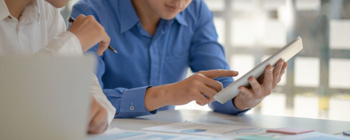 Midsection of woman holding mobile phone at table