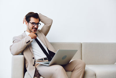 Young woman using laptop while sitting on sofa at home