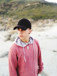 Young man wearing cap standing at beach