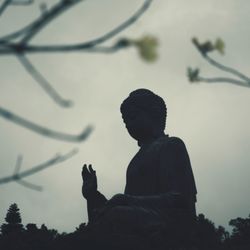 Low angle view of silhouette man using smart phone against sky