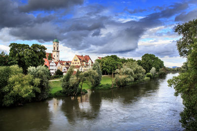 Scenic view of river by buildings against sky