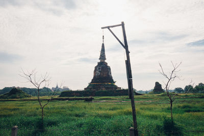 View of temple on field against cloudy sky