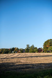 Hay bales on field against clear blue sky