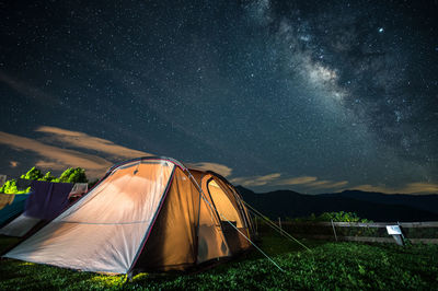 Illuminated tent on land against sky at night