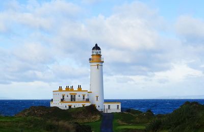 Lighthouse amidst sea and buildings against sky