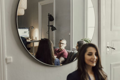 Reflection in mirror of coworkers during meeting