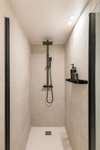 Modern shower zone with black rain head and hand held shower. beige tiles in the bathroom.