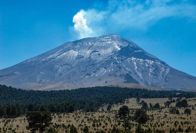 Scenic view of snowcapped  volcano mountains against blue sky